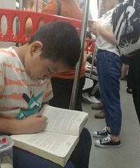 地铁上少年专心看书 周围大人全在看手机