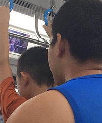 小孩子在轻轨上吊把手,哥哥还鼓励