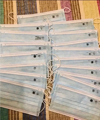 上小学的孩子要开学了,妈妈在准备好的口罩上写上名字,防止拿错