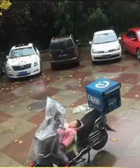 3岁女孩雨天电动车上酣睡 因无人照看母亲带其送外卖